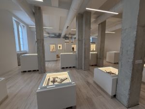 Vue de la salle d’exposition du Musée spiritain des arts africains à Allex, avec vitrines basses et piliers de béton brut.